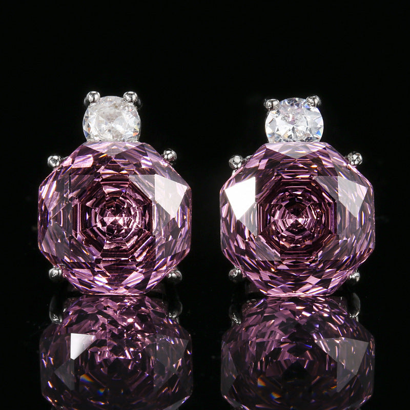 Pair of pink gemstone earrings with clear stones on a black background
